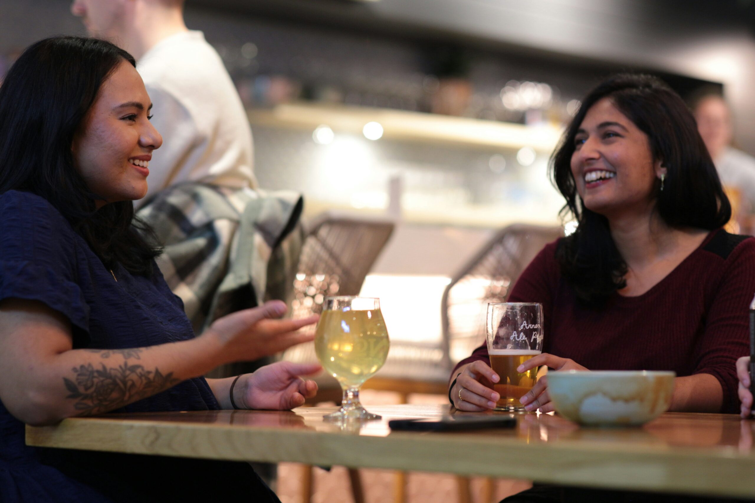 two women sitting at a table with wine glasses